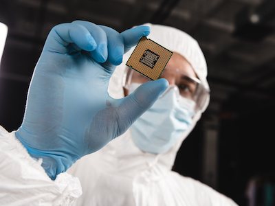 Scientist holds up microprocessor manufactured in innovative facility by amts in houston, texas.