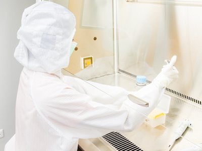 Researcher using cleanroom glove box to perform research following NEBB certification of the unit