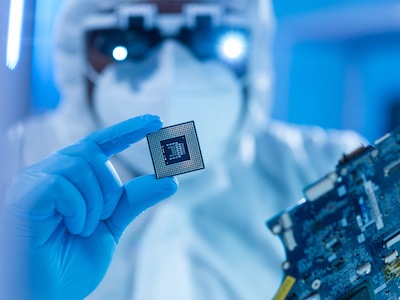 Researcher holding a semiconductor device in a cleanroom facility